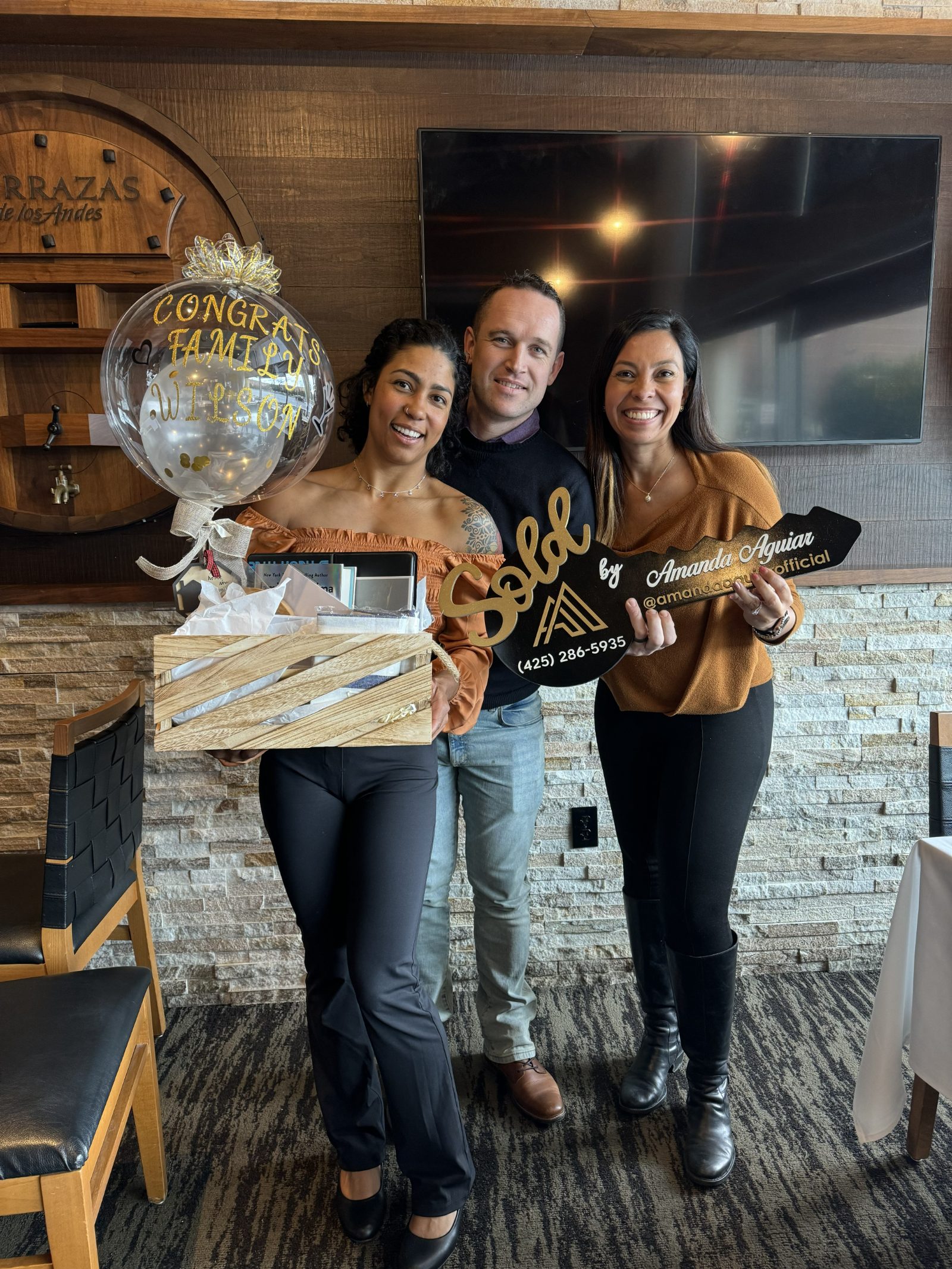 Amanda Aguiar with clients on closing day, holding the Sold key at their new home